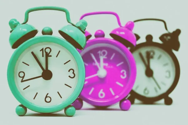 Vibrant set of vintage alarm clocks in teal, pink, and black.