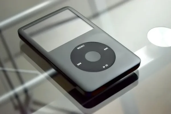 Close-up of a vintage MP3 player on a reflective glass table, showcasing its design.