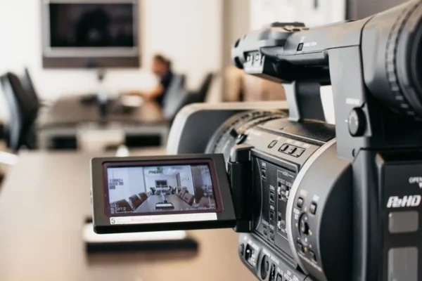 Close-up of professional video camera recording in modern office environment.