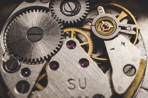 Detailed view of metal gears and components in a clock, highlighting precision engineering.