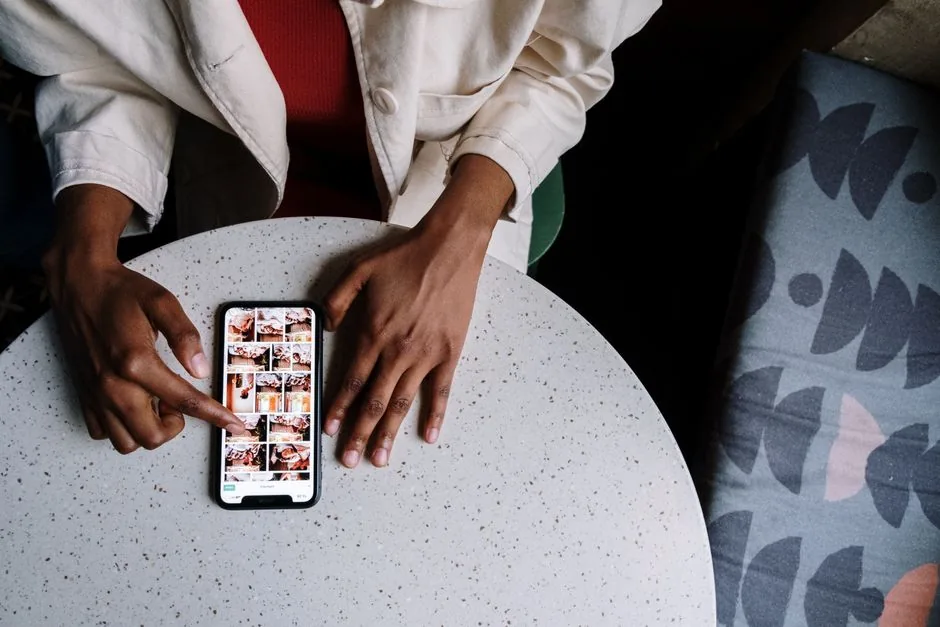 Overhead view of a person browsing photos on a smartphone at a cafe table with a touchscreen.