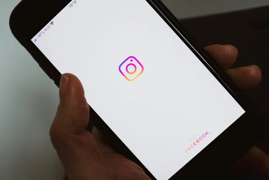 Crop faceless person taking mobile phone and demonstrating blank screen with social media app logo while having break and surfing internet