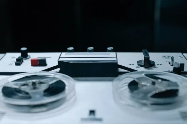 Close-up image of a vintage reel-to-reel audio recorder with control buttons and tape reels.
