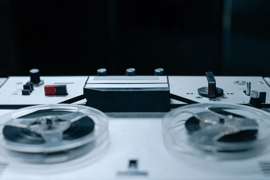 Close-up image of a vintage reel-to-reel audio recorder with control buttons and tape reels.